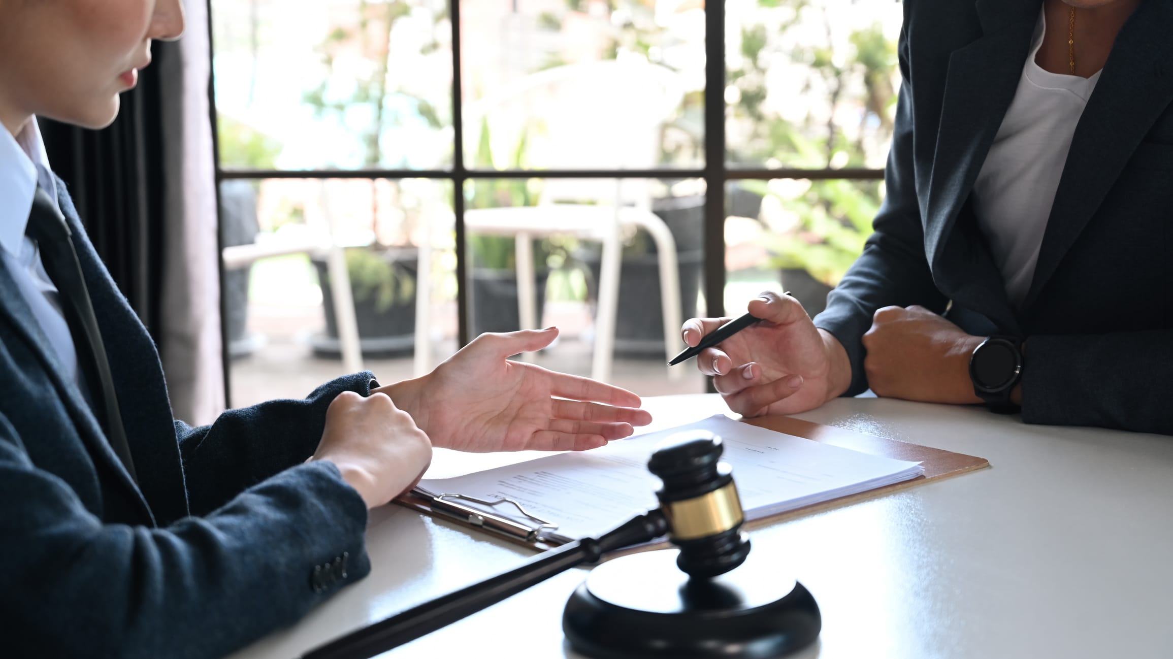 Personal injury attorneys gesture to one another while sitting at the negotiation table.