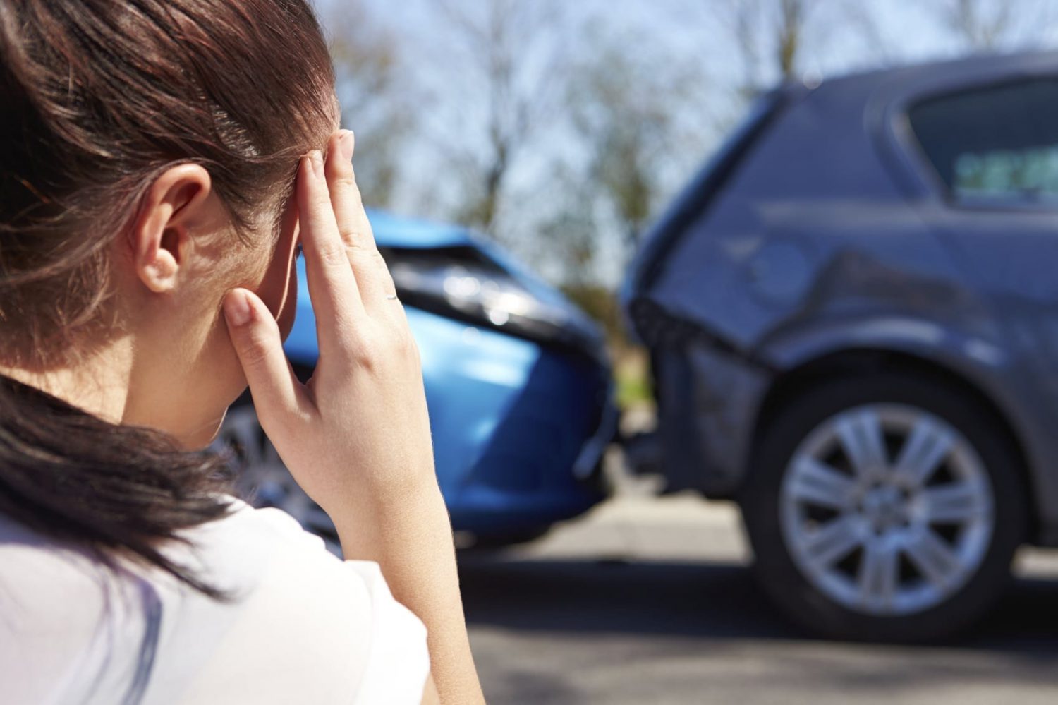 Woman Examining Rear End Car Accident Stock Photo