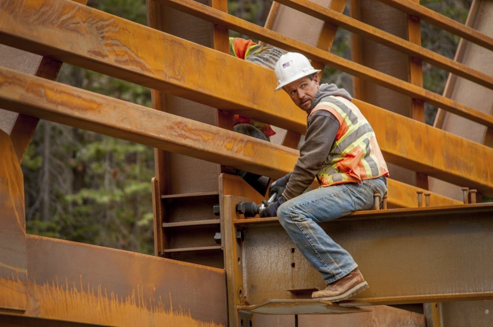Construction Worker Sitting On The Structure Of A Bridge Stock Photo