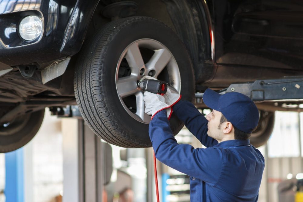 Mechanic Changing A Tire In An Auto Body Shop Stock Photo