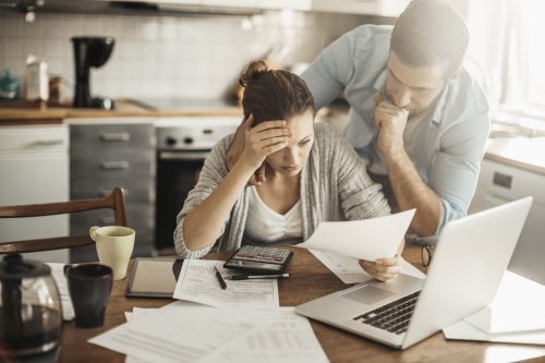 Distressed Couple Reviewing Bills At Their Table