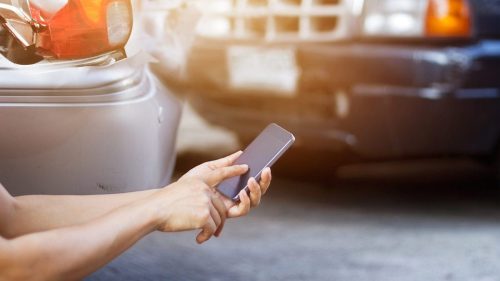Man Using His Smart Phone To Report A Car Accident Stock Photo