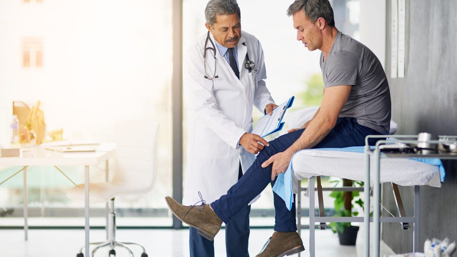 Doctor Examining A Man With A Knee Injury Stock Photo