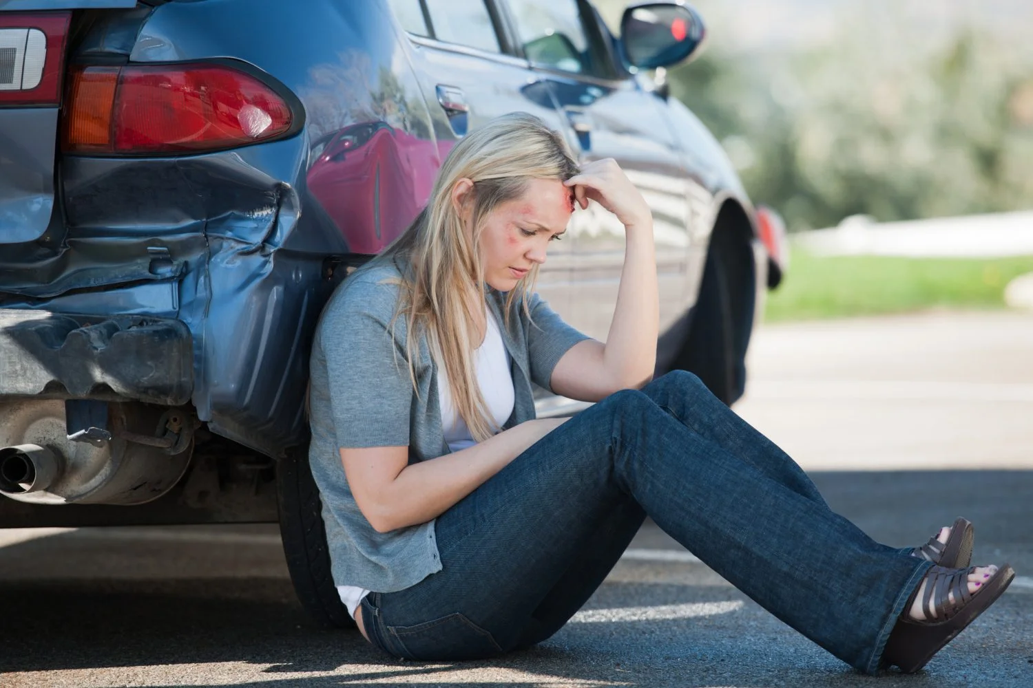 A woman leaning against her car after being injured in a Fort Wayne car accident.