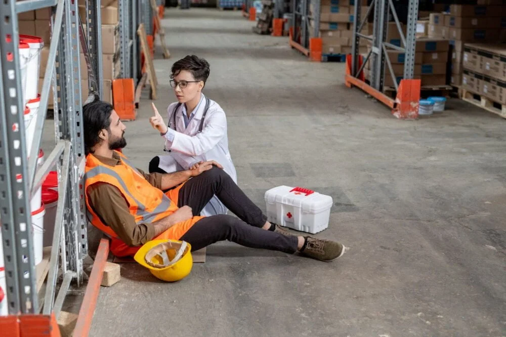 A doctor examines a warehouse worker who has been injured on the job.