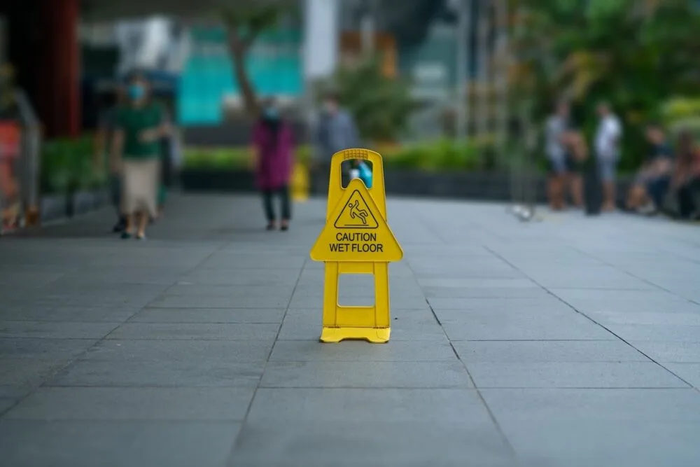 A wet floor sign in the middle of an outdoor walkway.