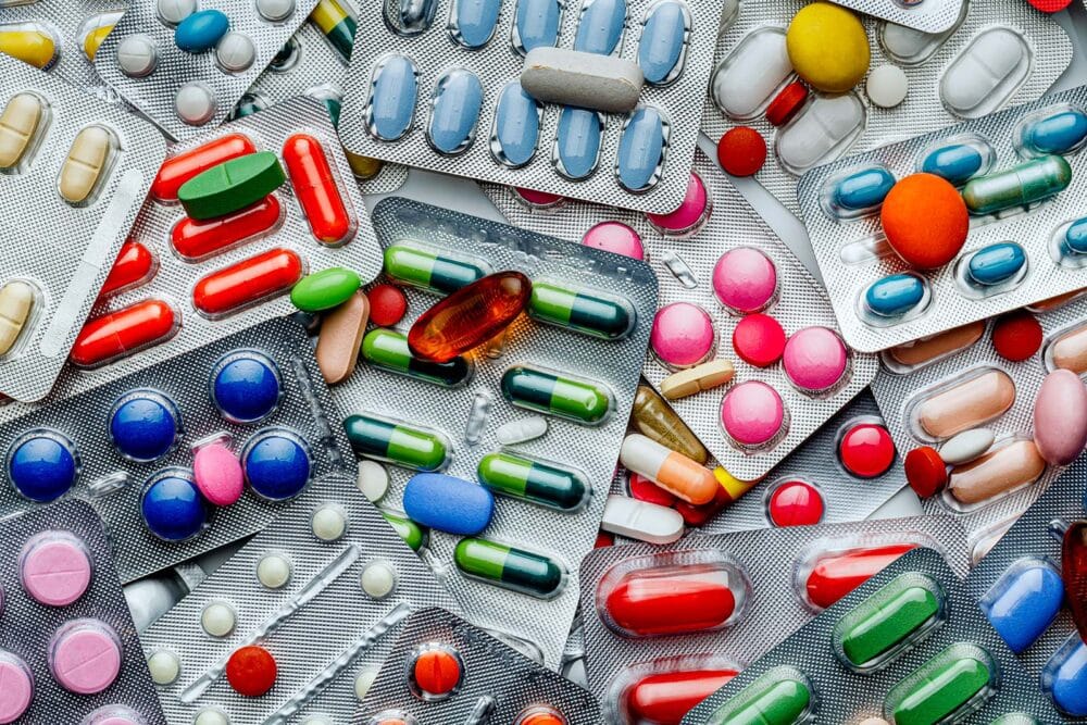 An assortment of prescription drugs in bubble packs and out of packaging.