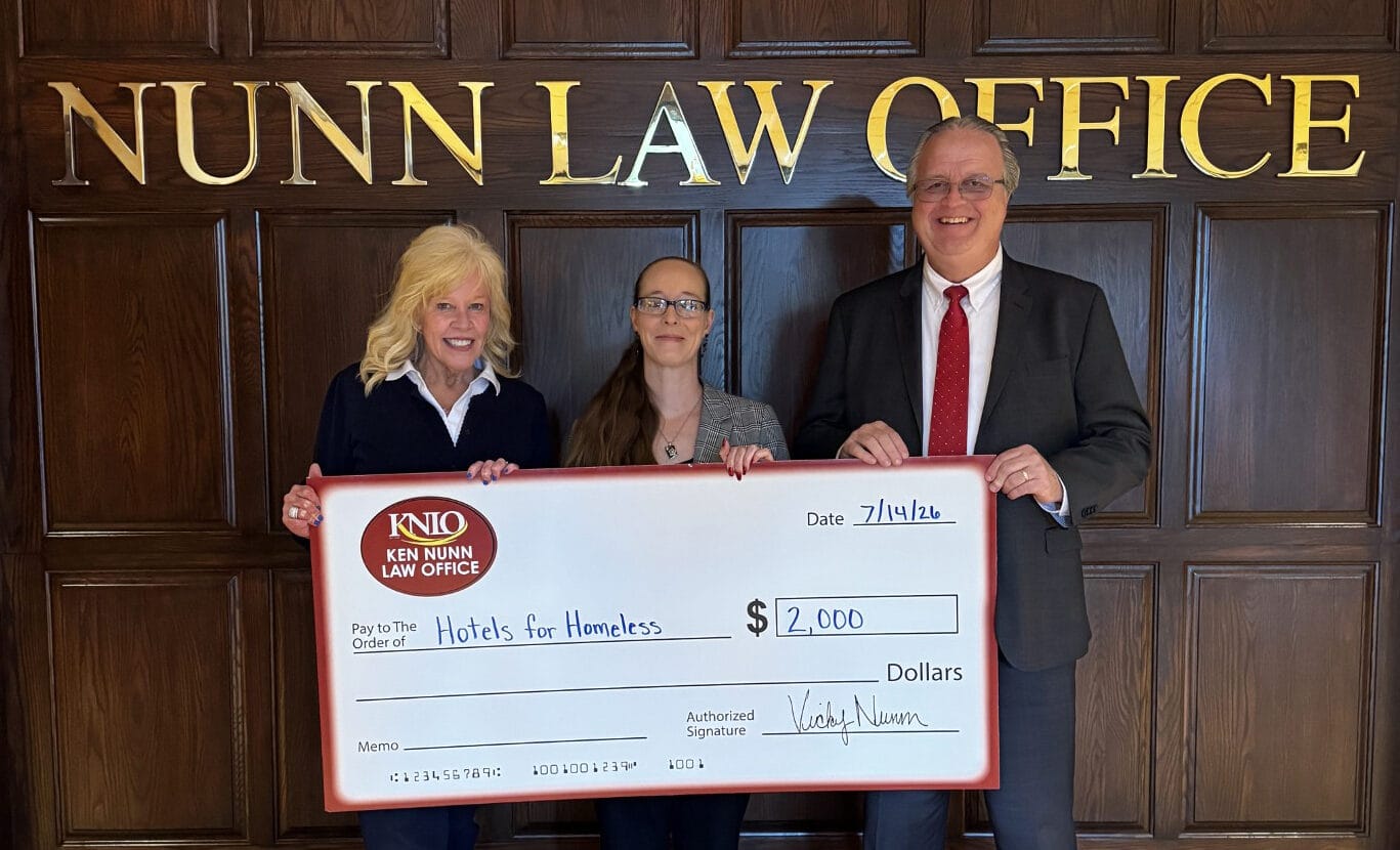 Attorneys Vicky Nunn and Dean Arnold with Katie Norris of Hotels for Homeless holding a donation check.