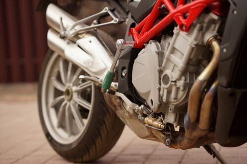 Close-up on the side of a motorcycle standing on brick pavement.